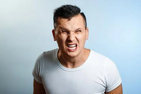 Portrait of a man close-up, experiencing anger, hate, against a light backgro Stock Photos