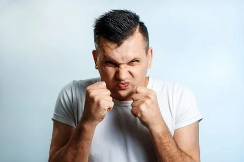Portrait of a man close-up, experiencing anger, hate, against a light backgro Stock Photos