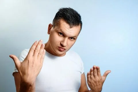 Portrait of a man close-up on a light background, shows a gesture with hands  Stock Photos