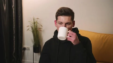 Portrait of a man drinking coffee or tea from a white cup while taking a break Stock Footage 148384050