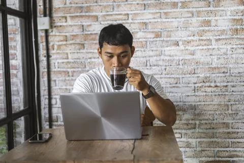 Portrait of a man drinking coffee while working on his laptop Stock Photos