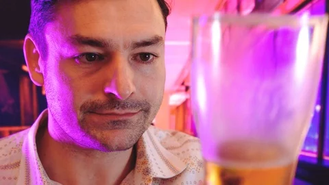 The portrait of man drinking dark beer interior background with Cool Neon Lights Vidéo 101914572