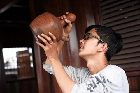 Portrait of a man drinking water using a kettle and glass made of clay Stock Photos