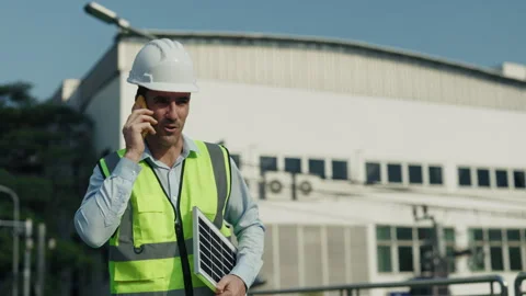 Portrait of man engineer in helmet talking on phone walking along construction Stock Footage 304705023