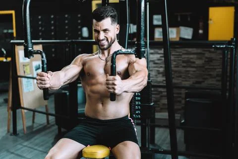 Portrait of a man exercising with weights using a machine in a gym Stock Photos