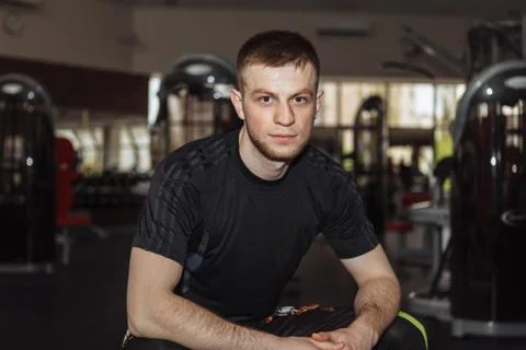Portrait of a man in the gym. The guy sat down to rest before performing stre Stock Photos