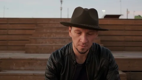 Portrait of a man in a hat and leather jacket. The man in the hat looks at the Video stock 121806285