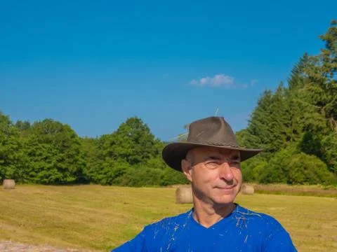 Portrait of a man in a hat behind a haystack in the field.. Stock Photos