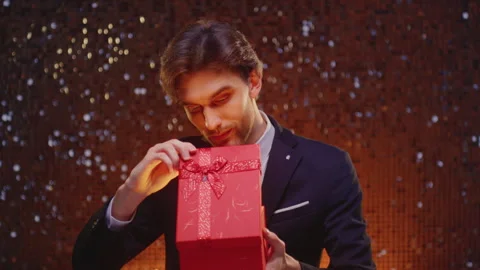 Portrait: man holding box bow, open surprise gift. Male in suit opens the Stock Footage 323999032