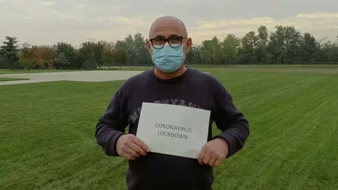 Portrait of Man Holding Covid Lockdown Sign While Wears a Medical Mask Stock-Footage 141920031