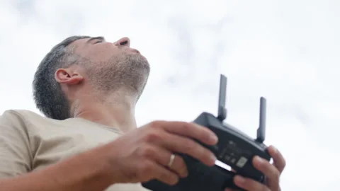 Portrait of man holding drone remote control against overcast sky. His gaze is Video stock 321887097