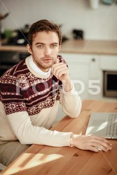 A portrait of a man at home with a laptop. Casual spring fashion, gadgets for Stock Photos