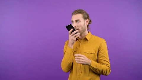 Portrait of a man on an isolated purple background recording a voice message, 4K Stock Footage 149043395