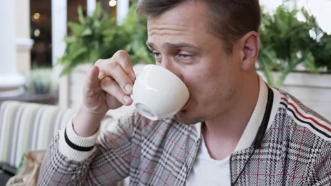 Portrait of man in jacket close up drinking coffee in an outdoor cafe Stock Footage 138774159