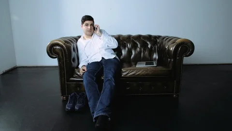 Portrait of Man on Leather Sofa Talking on Cell Phone Stock Footage 120422262