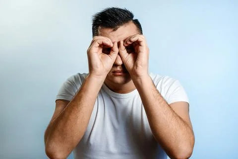 Portrait of a man on a light background, Makes binoculars from the hands, far Stock Photos