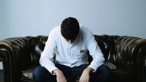 Portrait of Man Looking Up and Down Seated on Leather Couch Stock Footage 120425182