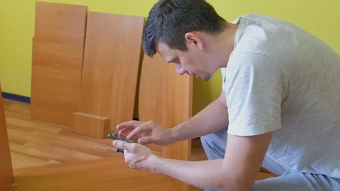 Portrait of man looking instruction in smartphone to collect table, side view. Stock Footage 124894257