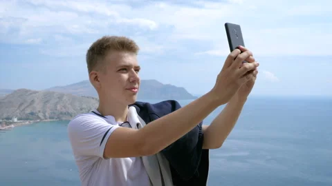 Portrait of a man making selfie on the background of mountains and sky. Video stock 96867843