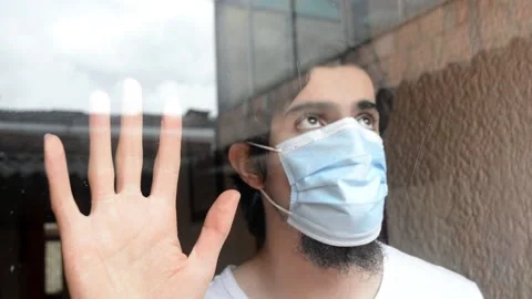 Portrait of a man with mask looking through the window, sky n buildings reflexed Stock Footage 143355686