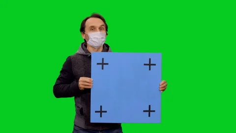 Portrait of man in mask presenting with blank blue placard on green screen 스톡 동영상 130794796