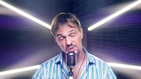 Portrait of a man with a mustache and a beard singing into a microphone on stage Video stock 161997334