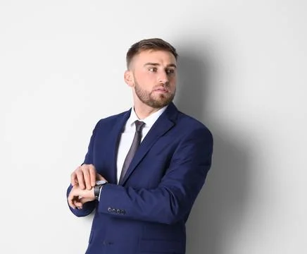 Portrait of man in office suit checking time on white background Stock Photos