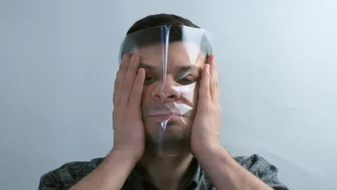 Portrait of man is puttion on plastic transparent film on his face. Stock Footage 152712284