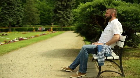 Portrait man sits on a bench at the park Stock Footage 64283690