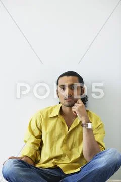 Portrait of man sitting on floor with hand on face Stock-Fotos