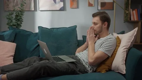 Portrait of man sitting at sofa and working remote on computer desktop in cozy Stock Footage 150436991