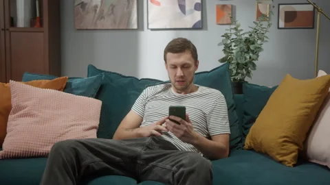 Portrait of man sitting at sofa and waiting for accept job offer or success bet Stock Footage 150438235