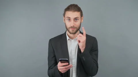 Portrait of a man with a smartphone on a gray background isolated. A man reads Stock Footage 154175556