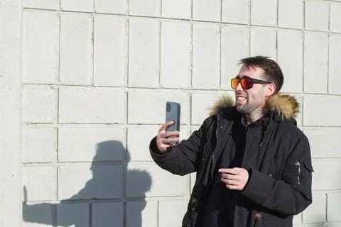 Portrait of man smiling while taking a selfie, wearing sunglasses and parka Stock Photos