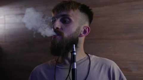 Portrait of a man smoking a hookah on a dark background Stock Footage 204842576