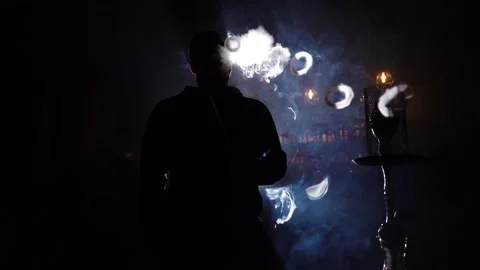 Portrait man smoking  hookah pipe and making smoke clouds in form rings. Vidéo 149250360