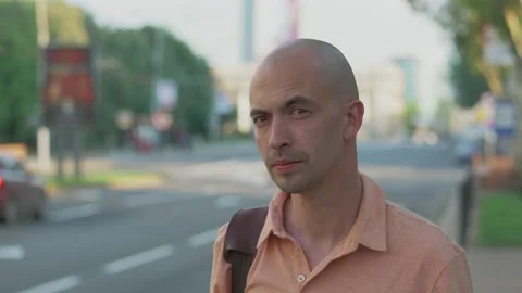 A portrait of a man standing at a bus stop in the city center, looking into the Stock Footage 155069076
