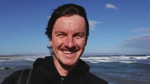 Portrait of a Man Standing by the Ocean in the Wind Stock Footage 310952291