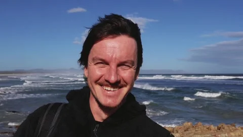 Portrait of a Man Standing by the Ocean in the Wind Stock Footage 310952346