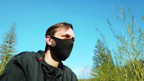 Portrait of a man taking off black protective neoprene face mask at the nature.  Video stock 130502208