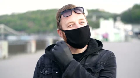 Portrait of man taking off face mask, blowing rubber glove. Video stock 129543084