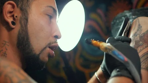 Portrait of man tattoo master with dreadlocks showing process of creation tattoo Stock Footage