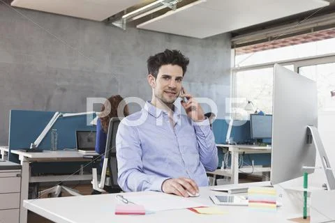 Portrait Of Man Telephoning With His Smartphone At His Workplace In The Office