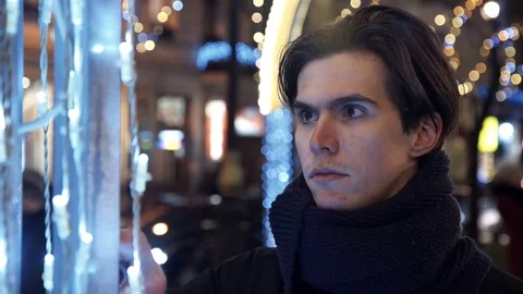 Portrait of man touching light bulbs on decorations standing at night in city Stock Footage 83630236