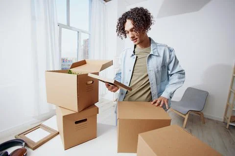 Portrait of a man unpacking things from boxes in the room sorting things out Stock Photos