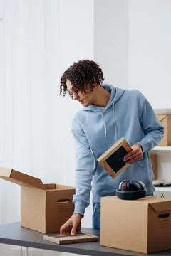 Portrait of a man unpacking things from boxes in the room sorting things out Stock Photos