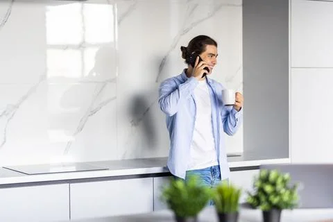Portrait of man using cellphone and drinking coffee while having breakfast at Stock Photos