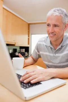 Portrait of a man using a notebook while drinking coffee Stock Photos