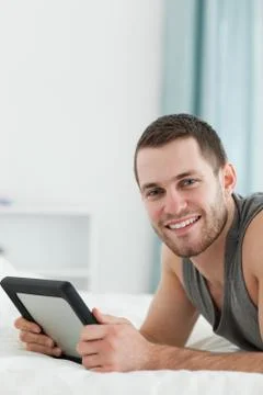 Portrait of a man using a tablet computer while lying on his belly 스톡 사진