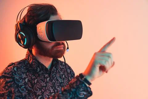 Portrait of a man with a vr headset and headphones touching the invisible Stock Photos